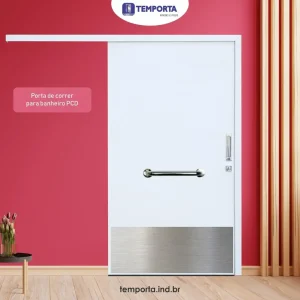 Porta de correr para banheiro PCD em madeira branca, com barra de apoio horizontal e chapa inferior de proteção, instalada em ambiente acessível.