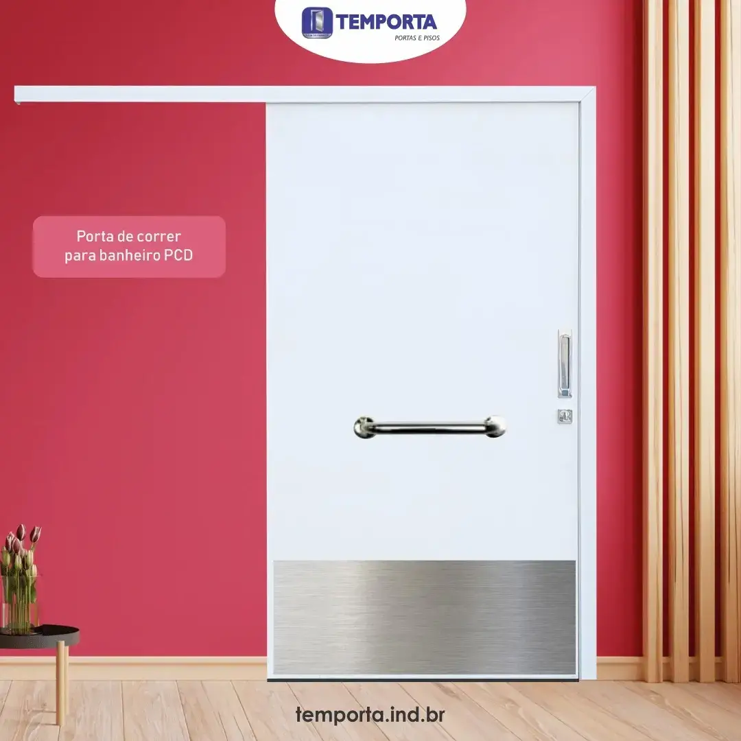 Porta de correr para banheiro PCD em madeira branca, com barra de apoio horizontal e chapa inferior de proteção, instalada em ambiente acessível.