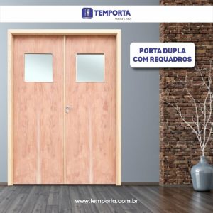 Porta dupla de madeira clara com design moderno e requadros, cada folha com visor quadrado de vidro fosco na parte superior, instalada em ambiente interno contemporâneo com parede cinza, detalhe em tijolo aparente e piso amadeirado escuro. À direita, jarro decorativo de cerâmica com acabamento brilhante e galhos secos. Imagem promocional da Temporta Portas e Pisos com destaque para “porta dupla com requadros.